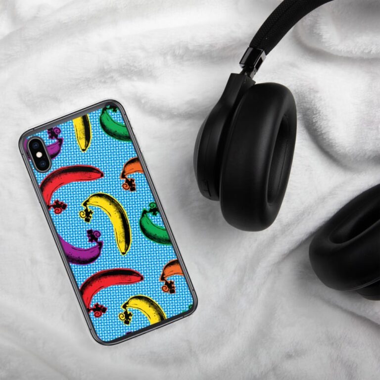 Colorful banana-patterned phone case beside black headphones on a soft white surface.