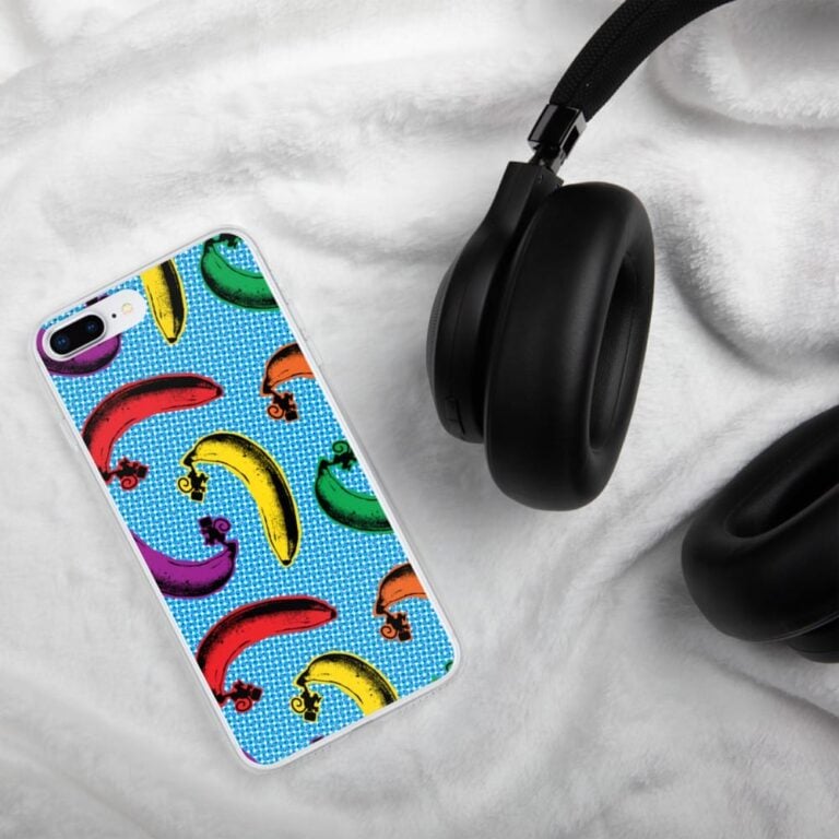 Colorful banana-patterned phone case beside black headphones on a soft white surface.