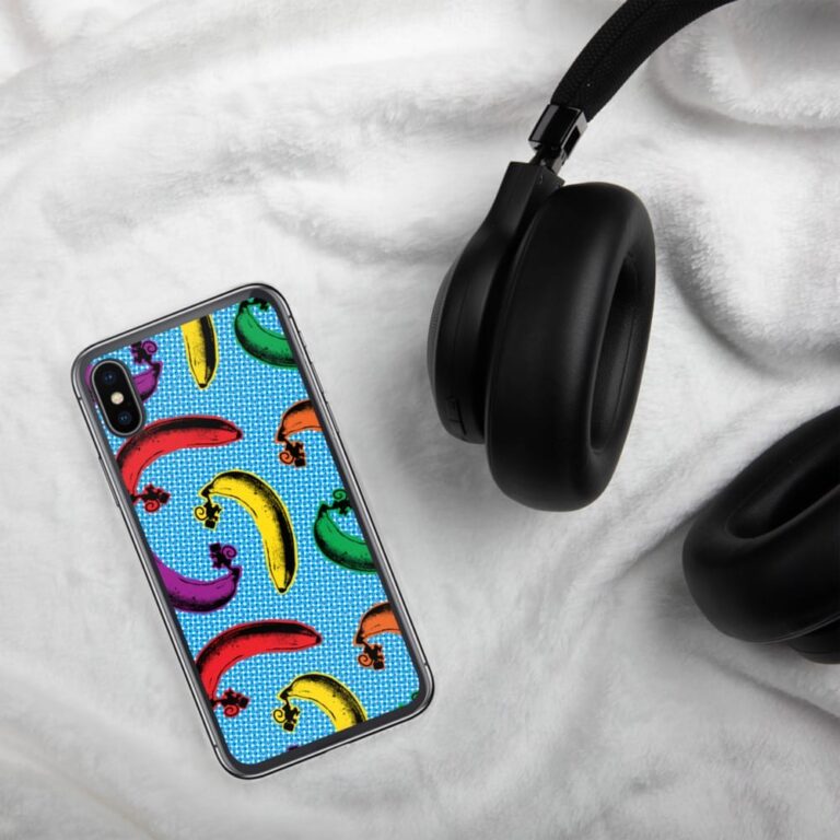 Colorful banana-patterned phone case beside black headphones on a soft white surface.