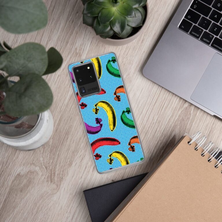 Colorful phone case with banana and chili pepper designs on a blue background, surrounded by plants and a laptop.