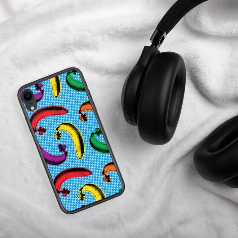 Colorful banana-patterned phone case beside black headphones on a soft white surface.