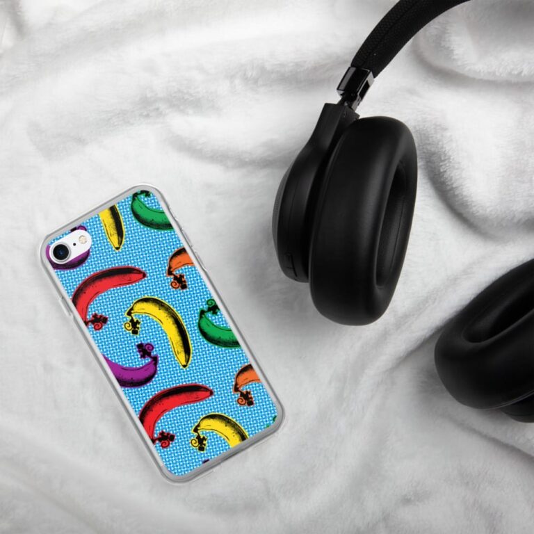 Colorful banana-patterned phone case next to black over-ear headphones on a soft white surface.